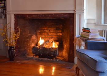 Pryor House B&B guest parlor, lit fireplace, with a blue chair.